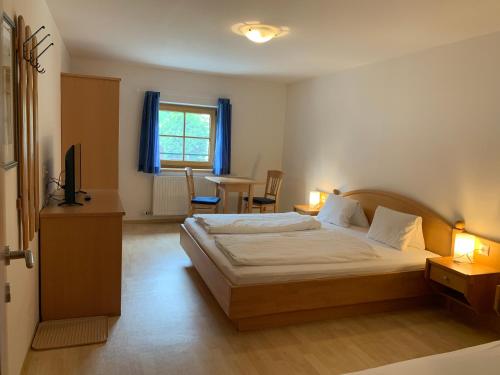 1 dormitorio con 1 cama y 1 mesa con sillas en Appartement Hammerschmidt, en Maishofen