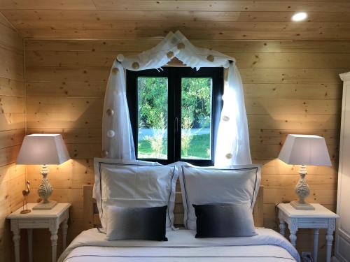 a bedroom with a bed with a window and two lamps at Moulin de la Chevriere in Saché