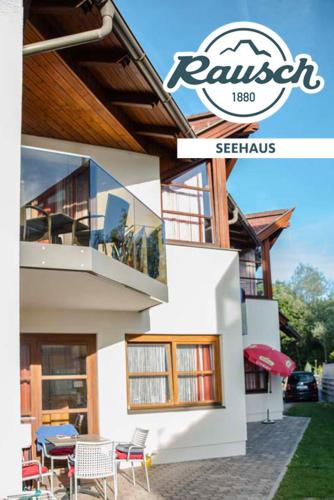 a house with chairs and tables in front of it at Seehaus Rausch in Egg am Faaker See