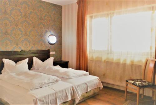 a bedroom with a bed with white sheets and a window at Hotel Sonne in Sibiu