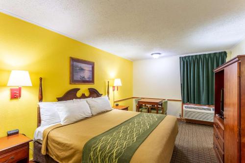 a hotel room with a large bed with yellow walls at Econo Lodge in Morgantown