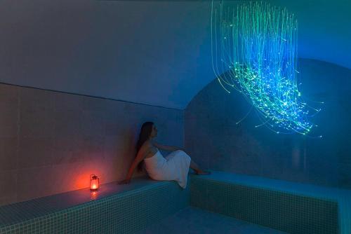 a woman sitting in a bath tub with a lit candle at Tenuta Santa Tecla in Acireale