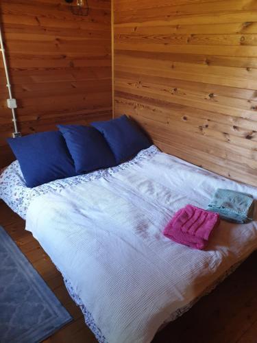 a bed with blue and white sheets and blue pillows at Domek letniskowy Nowy Prażmów in Prażmów Nowy