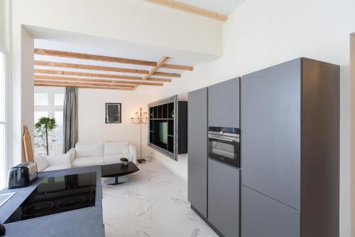 a kitchen with white walls and a living room at The Golden Gardens - R.Q.C. in The Hague