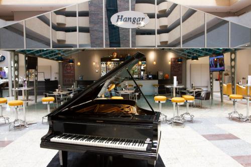 a piano in a mall with a bar with stools at Bristol International Guarulhos in Guarulhos