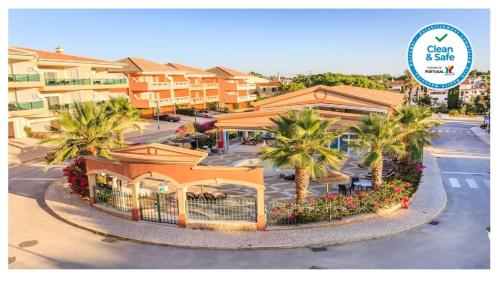 a building with palm trees in front of a street at Lakeside Country Club - Apartamentos Turísticos in Quinta do Lago