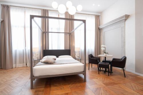 a bedroom with a canopy bed with a table and chairs at Hotel Palazzo Martinelli Dolfin in Venice