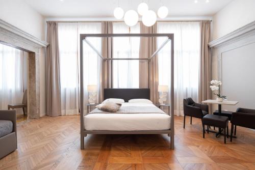 a bedroom with a canopy bed and a dining room at Hotel Palazzo Martinelli Dolfin in Venice