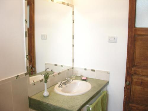 baño con lavabo y espejo grande en Ipacaa Lodge en Esquina