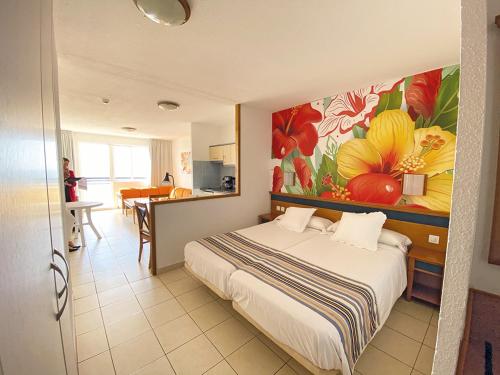 una camera da letto con un letto e un dipinto sul muro di Apartamentos Palm Garden by LIVVO a Morro del Jable
