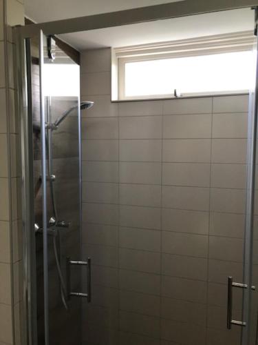 La salle de bains est pourvue d'une douche et d'une fenêtre. dans l'établissement Vakantiehuisje in Ouddorp dichtbij het strand, à Ouddorp