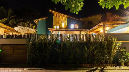 a house at night with a fence and an umbrella at Casa dos Mineiros in Arraial d'Ajuda