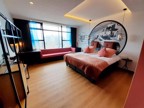 a bedroom with a large bed and a red couch at Palace Hotel Zandvoort in Zandvoort