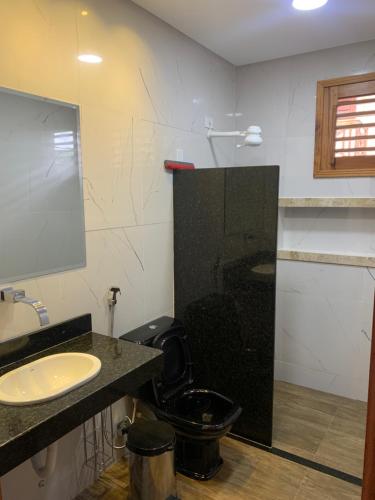 a bathroom with a black toilet and a sink at Sítio do Bosco Park in Tianguá