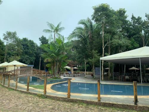 a pool at a resort with tables and umbrellas at Sítio do Bosco Park in Tianguá