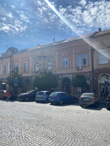 a large building with cars parked in front of it at Apartment suite Mukachevo in Mukacheve