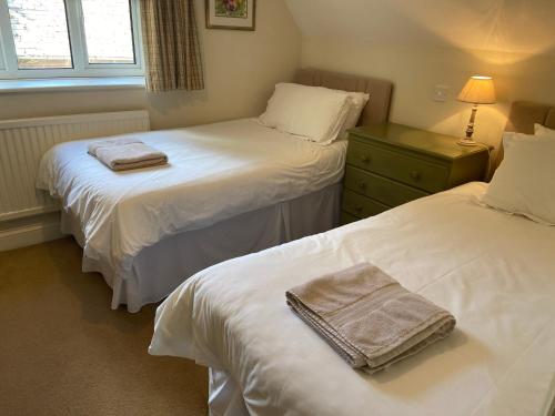 a room with two beds with towels on them at Far Hill Cottage in Wyck Rissington