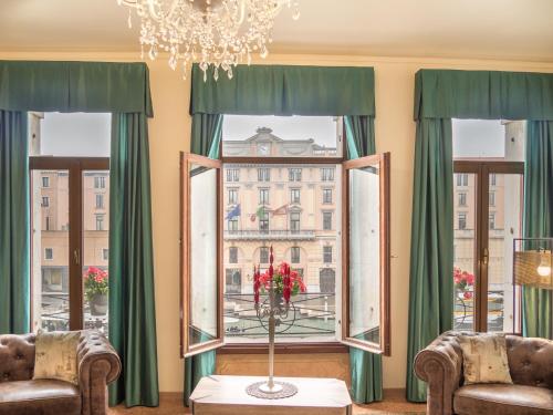 ヴェネツィアにあるGrand Canal Suite by Wonderful Italyの椅子2脚、窓(緑のカーテン付)が備わる客室です。
