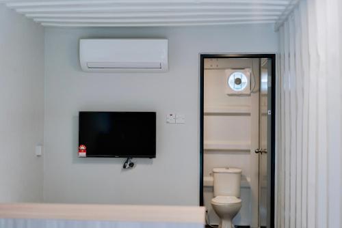 a bathroom with a toilet and a flat screen tv on the wall at Reserve The Cozytainer in Taiping