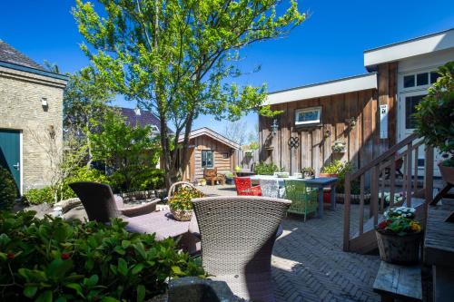 a patio with chairs and a table and a tree at Pastorie Stella Marie in Oudeschild