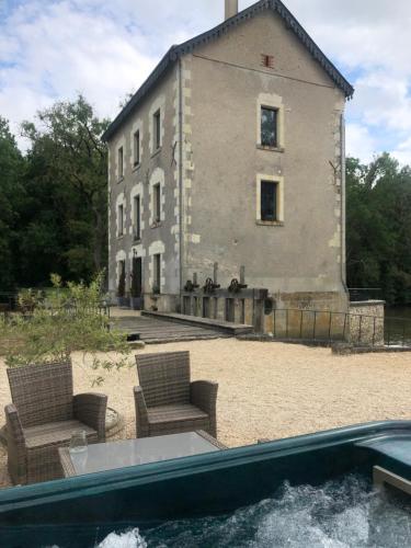 a building with chairs and a pool in front of it at Moulin de la Chevriere in Saché