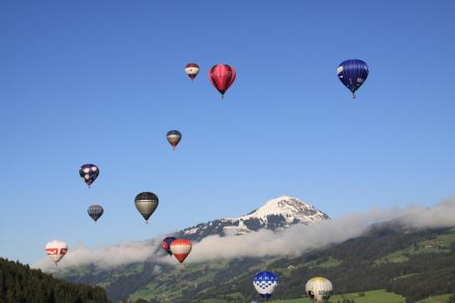 a group of hot air balloons flying over a mountain at Alpen Glück Hotel Kirchberger Hof in Kirchberg in Tirol