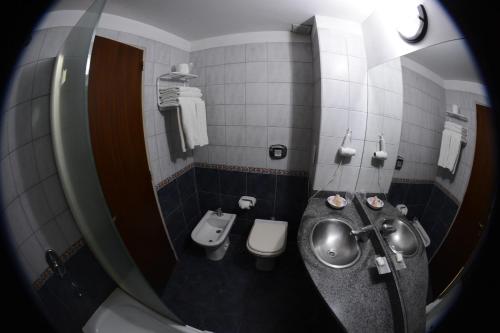 a bathroom with a toilet a sink and a mirror at Apart Hotel Alvear in Rosario