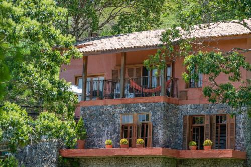 a pink house with a balcony and trees at Quinta dos Pinhais Pouso e Charme in Santo Antônio do Pinhal