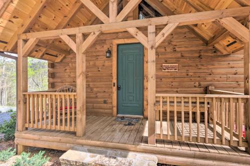 a wooden cabin with a green door on a deck at Elevated Cabin Bordering Smoky Mountain Natl Park in Bryson City