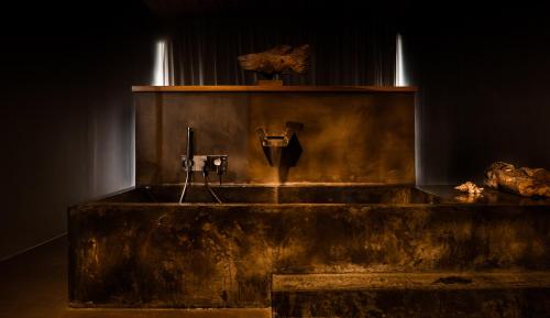 a wooden bathtub in a dark room with a statue at Santa Barbara Eco-Beach Resort in Ribeira Grande