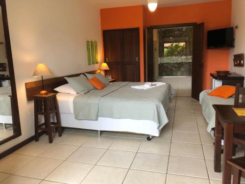 a bedroom with two beds with orange walls and a window at Pousada Caminho do Sol in Arraial do Cabo