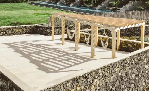 a picnic table on a stone wall with a shadow at Santa Barbara Eco-Beach Resort in Ribeira Grande