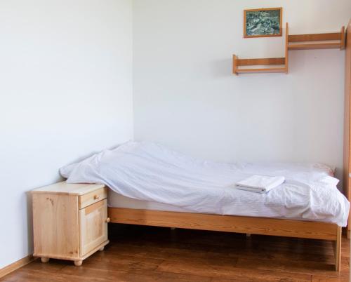 a bed with a nightstand next to a white wall at Noclegi u Banysia w sercu Gór Świętokrzyskich in Krajno Pierwsze