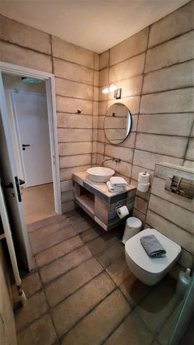 a bathroom with a toilet and a sink and a mirror at Voulas Apartments in Stoupa
