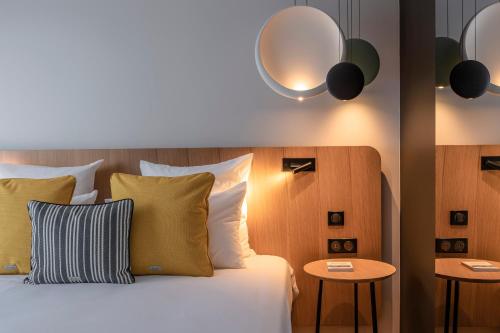 a bedroom with a bed with pillows and two tables at Hôtel Villa KOEGUI Bayonne in Bayonne