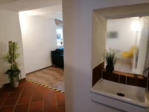 a bathroom with a sink and a living room at Creek Inn, Contactless Check-in in Glanbrücken