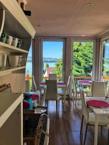 a restaurant with tables and chairs and a view of the water at Villa Borostyán in Tihany