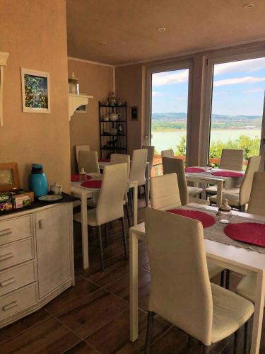 a dining room with tables and chairs and windows at Villa Borostyán in Tihany