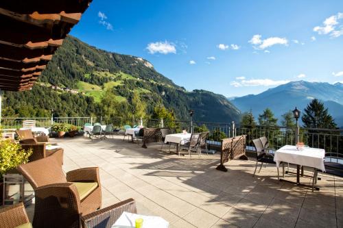 a patio with tables and chairs with mountains in the background at die Aussicht in Finkenberg