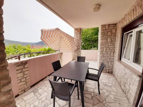 a table and chairs on a balcony with an umbrella at Apartments Mužić Cres II in Cres