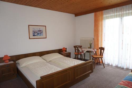 een slaapkamer met een bed en een tafel en stoelen bij Gästehaus Resei in Schiefling am See