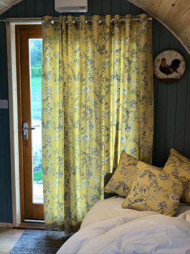 a bed with a yellow curtain next to a window at Orchard Glamping in Catterall