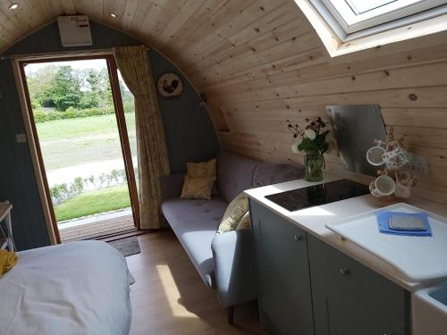 a room with a couch and a sink in a tiny house at Orchard Glamping in Catterall