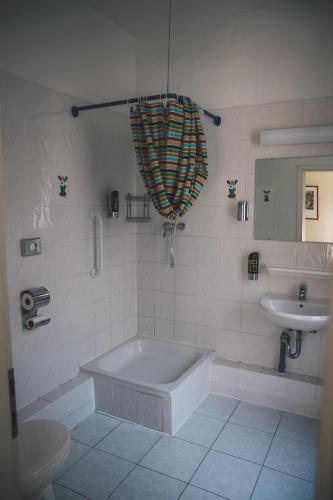 a white bathroom with a tub and a sink at Happy Hotel Berlin in Berlin