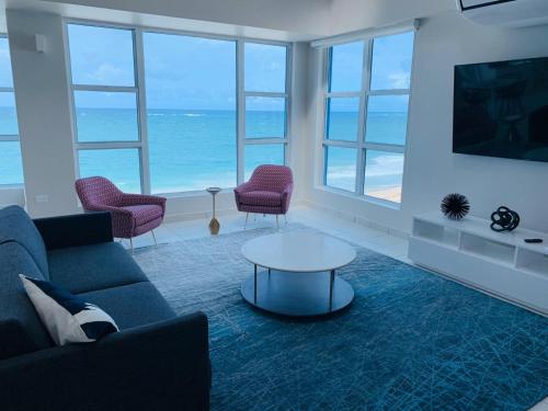 a living room with a couch and chairs and the ocean at The Tryst Beachfront Hotel in San Juan