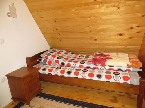 a bed in a room with a wooden wall at Rooms and Bungalows Sreten Žugić in Žabljak