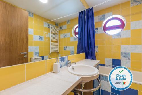 a yellow bathroom with a sink and a mirror at Marina de Albufeira Villa 8 in Albufeira