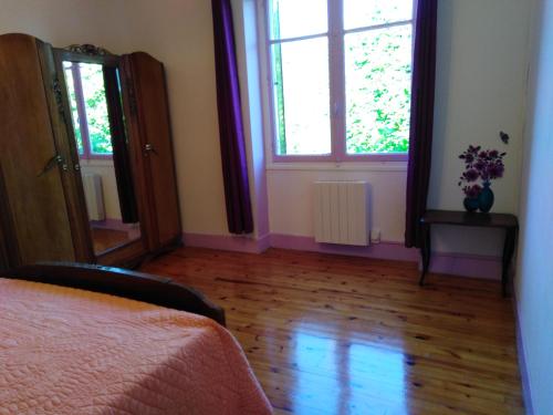a bedroom with a bed and two windows and a wooden floor at chez Patricia in Cransac
