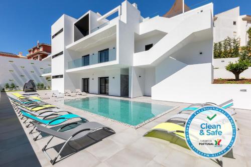 a villa with a swimming pool and lounge chairs at Luxury 47 in Albufeira