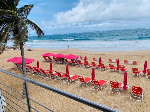 a group of chairs and pink umbrellas on a beach at The Tryst Beachfront Hotel in San Juan
